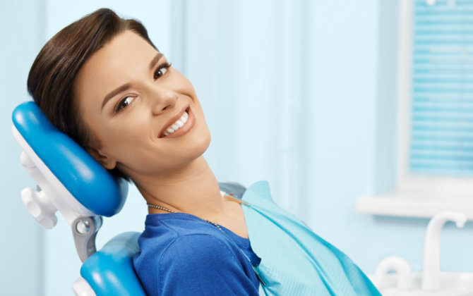 A woman smiling while sitting in a dental chair.
