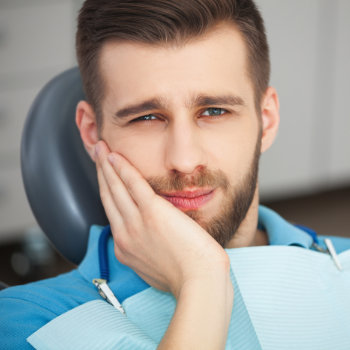 a young man with a toothache sitting in the dental chair