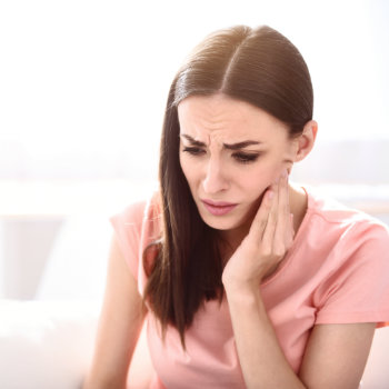 brunette with severe toothache touching her cheek
