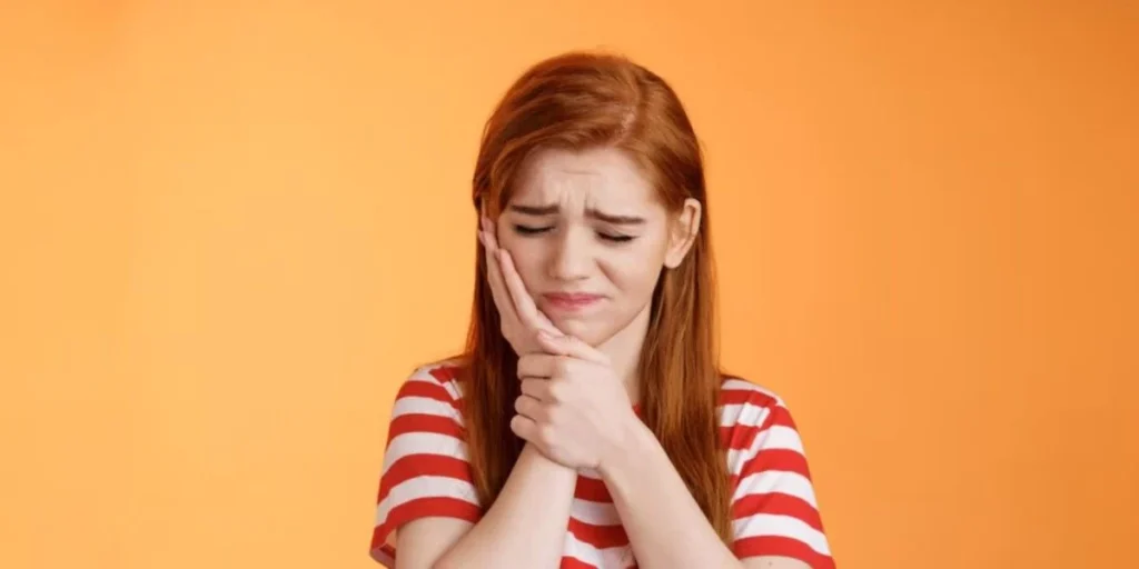 Young woman holding jaw from painful toothache symptoms